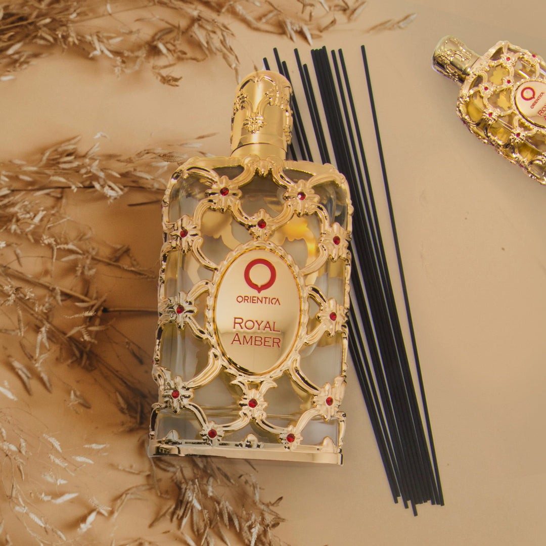 Decorative bottle of Orienta Royal Amber on a textured beige surface with incense sticks.